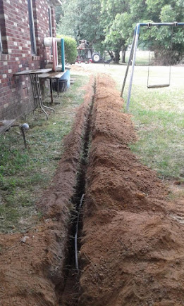 Freshly excavated sewer line trench across an Indianapolis backyard